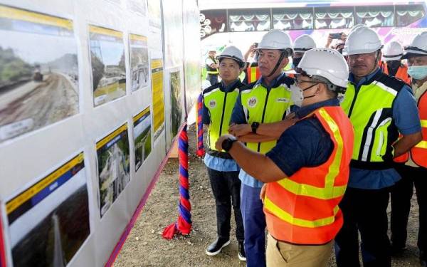 Fadillah (dua, kiri) diberikan taklimat sewaktu meninjau pembinaan Lebuhraya Pan Borneo sempena program jelajah raya pada Jumaat.