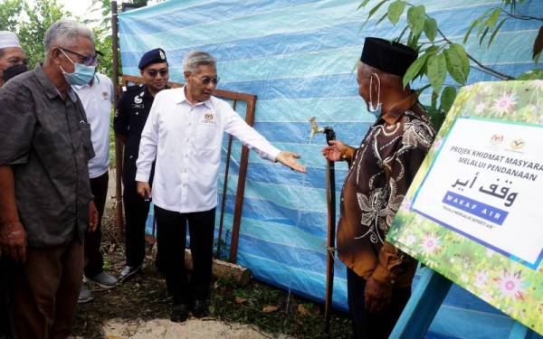 Mansor (dua dari kanan) menunjukkan air paip yang mengalir laju pada Malis Penyerahan Projek Wakaf Air di Kampung Padang Durian, Pendang hari ini. - Foto Bernama