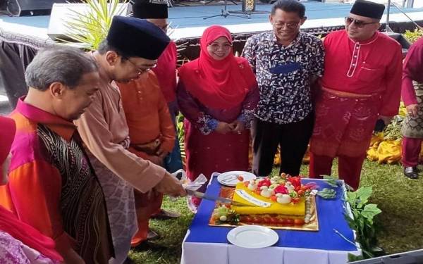 Zahidi (dua dari kiri) memotong pulut kuning pada Majlis Ramah Mesra Hari Raya Aidilfitri Timbalan Menteri Komunikasi dan Multimedia, di Padang MSPPK, Ambangan Height, Sungai Petani pada Sabtu.