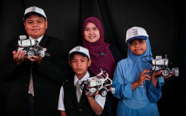 Pelajar Orang Asli, Mohd Haziq Hazry Hazroi, 10, (depan), Siti Raudah Mohd Hairy, 12 (kanan), John Lester, 12 (kiri) dan gurunya Nurain Nadiah Mohamed Junid bergambar bersama robotik pada Program Jelajah Aspirasi Keluarga Malaysia Negeri Terengganu 2022 di Kompleks Sukan Negeri Terengganu pada Khamis. - Foto Bernama
