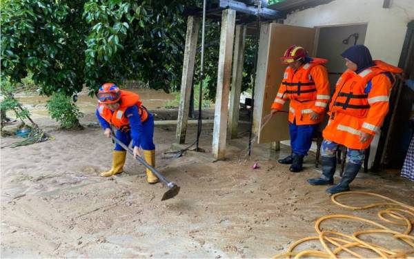 Anggota APM Kuala Muda membantu mencuci halaman rumah mangsa banjir di Gurun, pada Khamis.