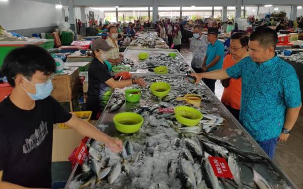 Jamal (kanan) bersama kepimpinan UMNO Bahagian Sungai Besar meninjau harga ikan di Pasar Awam Sungai Besar pada Ahad.