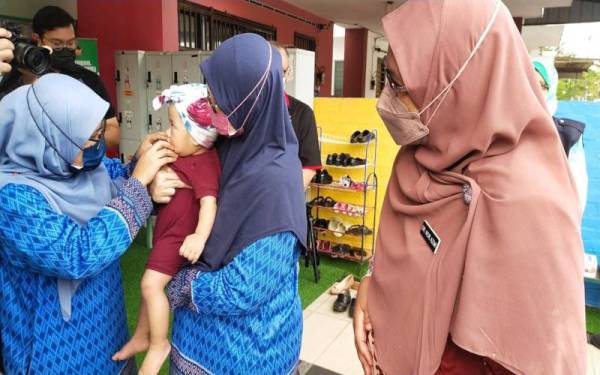 Dr Nor Azimi (kanan) meninjau aktiviti saringan awal terhadap kanak-kanak bagi mengesan gejala HFMD yang dijalankan kakitangan Taska Ar Raudah, Kotasas pada Rabu.