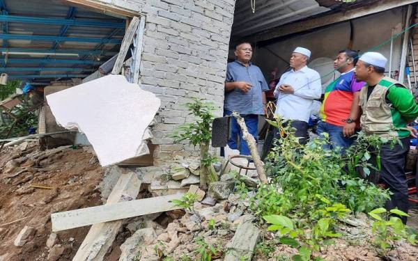 Azhar (kiri) menceritakan detik cemas kepada Wan Romaini (dua kiri) aoabila sebahagian rumahnya yang runtuh masuk ke dalam Sungai Padang Terap di Kepala Batas dalam kejadian pagi Isnin lalu.