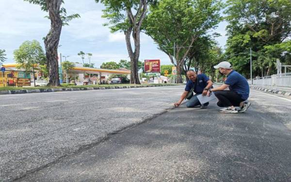 Eric (kanan) menunjukkan jalan raya yang tidak ditampal dengan baik.