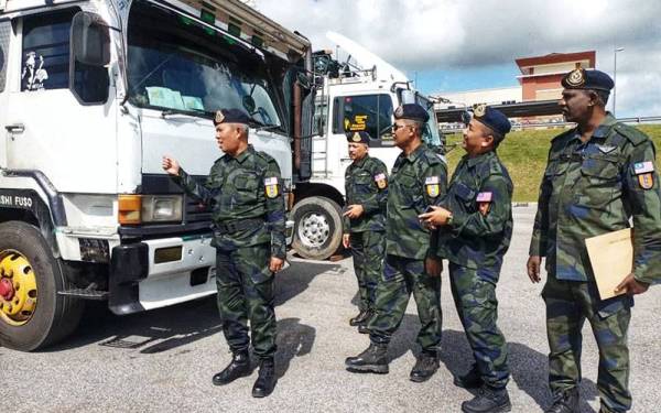 Shamsul Baharin (kiri) melihat treler yang dirampas ketika pemeriksaan di sekatan jalan raya Kilometer 1.1 Kompleks Imigresen, Kastam, Kuarantin dan Keselamatan (ICQS) di Bukit Kayu Hitam pada Selasa.