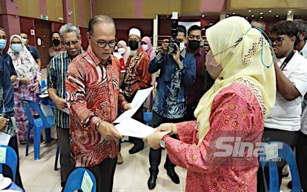 Wan Rosdy menyerahkan surat tawaran kepada salah seorang peserta Lot Ladang Sawit STR Batu 8 Lepar (Lot 5), Mukim Lepar dalam majlis penyerahan di Dewan Konvensyen Sultan Haji Ahmad Shah, Pekan pada Khamis.