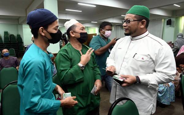  Muhammad Iqbal Rosli, 23,(kiri) menerima bantuan kewangan daripada Timbalan Menteri di Jabatan Perdana Menteri (Hal Ehwal Agama) Datuk Ahmad Marzuk Shaary (kanan) sempena Program Lambaian Kaabah di Dewan Haji Nik Abdullah Arshad, Kompleks Purnama di Pengkalan Chepa. - Foto Bernama
