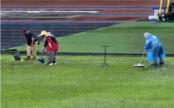 Beberapa petugas sedang menolak air yang bertakung menggunakan penyodok sampah di Stadium Nasional, Bukit Jalil pada Sabtu.
