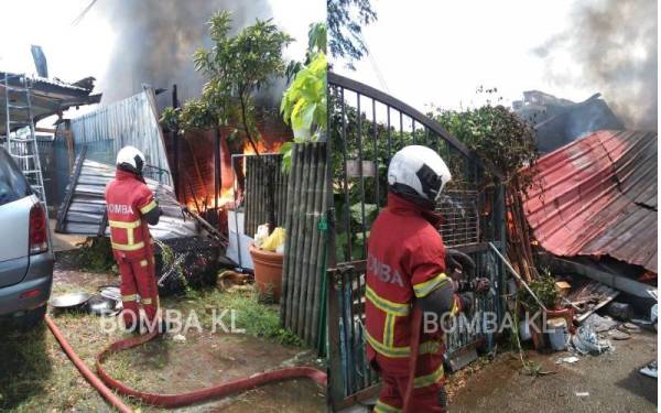 Anggota bomba bertungkus lumus memadamkan kebakaran melibatkan dua buah rumah di Jalan Jinjang Permai 2, Jinjang Utara di sini pada Isnin. - Foto Bomba KL