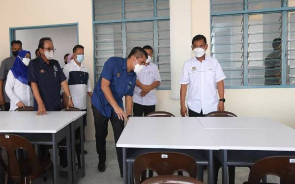 Mohd Radzi (tengah) melihat meja yang digunakan oleh pelajar sewaktu melawat kelas sekolah selepas merasmikan Sekolah Menengah Kebangsaan Libaran hari ini. Foto Bernama