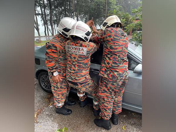 Tiga anggota bomba sedang membuka pintu kereta Proton Persona itu menggunakan peralatan khas.