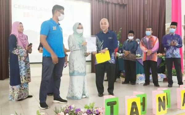 Rosli (tengah) menyerahkan slip keputusan SPM kepada pelajar terbaik calon SPM dari SMK Abdul Rahman Talib, Nur Arisha Amyrul Naim,18, sempena pengumuman keputusan peperiksaan SPM 2021 Negeri Pahang, Kuantan pada Khamis.