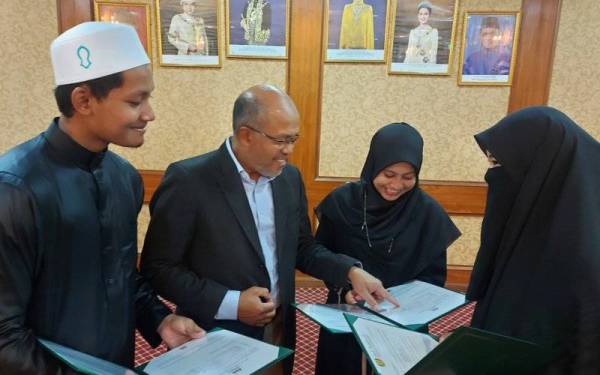 Wan Sabri (dua dari kiri) melihat surat tawaran yang diterima tiga pelajar tahfiz yang mengikuti UBC berikutan memperoleh keputusan cemerlang pada SPM 2021 di USAS pada Jumaat.