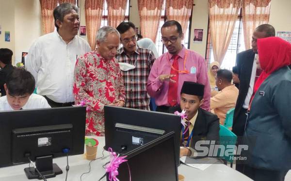 Muhammad Nasir (tiga,kiri) mendengar penerangan dari guru ketika hadir melihat penggunaan komputer sumbangan TMESA di makmal komputer SMK Tengku Mahmud, di sini pada Ahad.