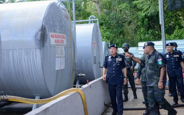 Muhamad Zaki (kiri) bersama para pegawainya melihat tangki minyak diesel yang dirampas ketika melawat lokasi serbuan di syarikat pembekal minyak diesel di Kampung Tebing Tinggi pada Ahad. - Foto Bernama 