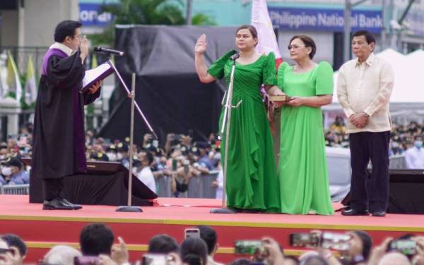 Duterte-Carpio (tengah) mengangkat sumpah di hadapan hakim bersekutu Mahkamah Agung, Ramon Hernando dan turut diiringi ibu dan bapanya, Duterte. - Foto AFP