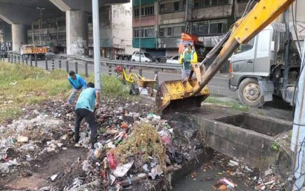 Pihak JPP MPK menjalankan kerja pembersihan sampah dalam saliran di pekan Pelabuhan Klang yang menjadi punca banjir kilat. - Foto Facebook Azmizam Zaman Huri