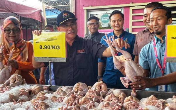 Ronald Kiandee (dua dari kiri) menunjukkan harga ayam yang dijual di pusat jualan Bismi Empire Sdn Bhd, pada Selasa.