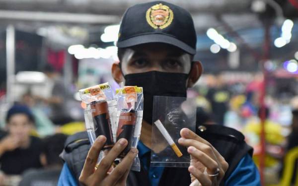 Pembantu Kesihatan Awam, Jabatan Kesihatan Negeri Terengganu, Muhamad Faiz Abdullah menunjukkan rokok dan rokok elektronik yang dirampas menerusi 'Op Gomo Asap Malam' di sebuah medan selera malam Selasa.- Foto Bernama