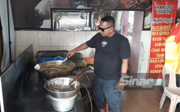 Zulkarnain menggoreng ayam di kedainya di Kangkar Tebrau, Johor Bahru, pada Rabu.