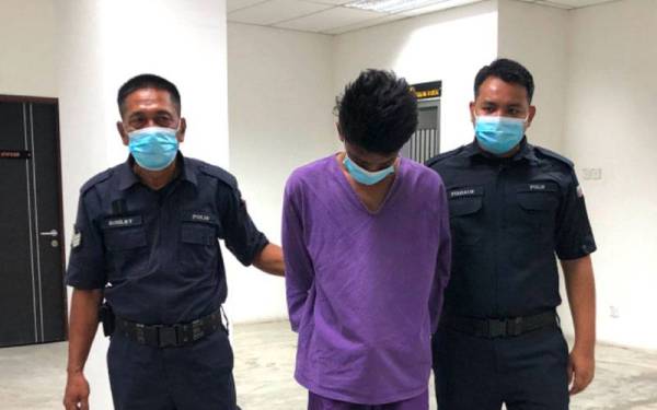 Suspek (tengah) dikawal polis ketika dibawa keluar dari Lokap Mahkamah Kota Bharu menuju ke Mahkamah Majistret Kota Bharu bagi mendapatkan perintah reman.