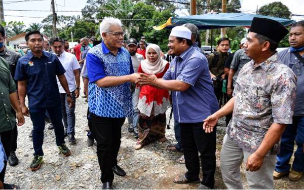 Hamzah (kiri) menyantuni penduduk setempat ketika menghadiri Program Kenduri Rakyat Kampung Anak Kurau di sini pada Sabtu. - Foto Bernama 