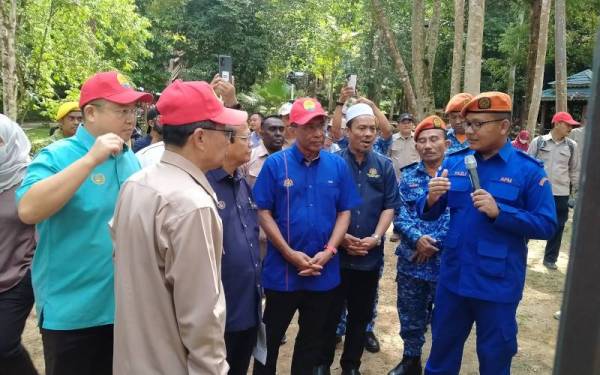 Takiyuddin (empat dari kanan) mendengar taklimat semasa hadir ke lokasi tragedi kepala air Titi Hayun Yan Kedah pada Ahad.