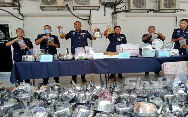 Vijaya (tiga dari kiri) menunjukkan minyak masak yang disembunyikan dalam cerek yang berjaya dikesan menerusi serbuan di sebuah premis di Bandar Baru Klang pada Isnin.