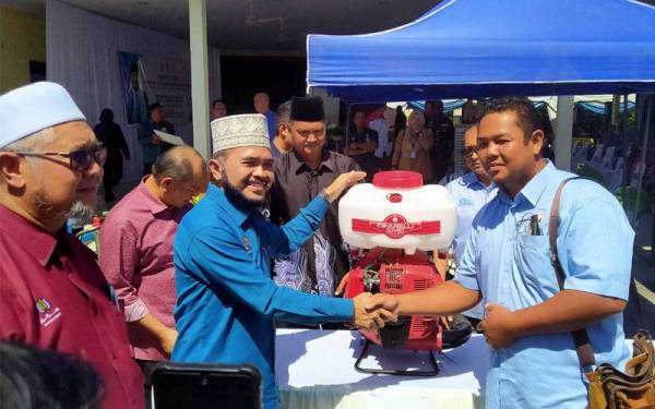 Nik Muhammad Zawawi (dua dari kiri) menyerahkan peralatan pertanian kepada penerima ketika mengadakan lawatan kerja ke Pejabat Pertubuhan Peladang Kawasan Gunung Semanggol/Selinsing, di sini pada Khamis.