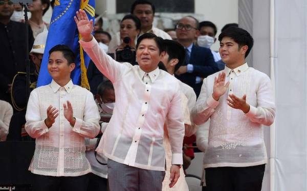 Presiden Filipina baharu, Marcos Jr yang diapit anaknya melambaikan tangan kepada penyokong di Manila. - AFP