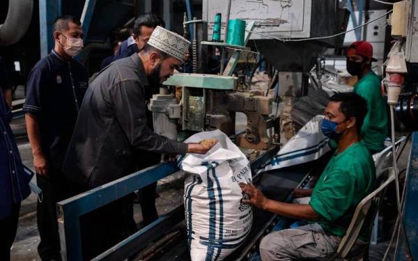 Nik Muhammad (dua, kiri) melihat benih padi yang telah diproses ketika melakukan lawatan di Pusat Pengeluaran Benih Padi Pertubuhan Peladang Kawasan Lahar Bubu pada Jumaat. - Foto Bernama 