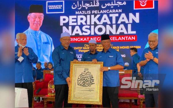 Muhyiddin (dua dari kanan) menerima cenderamata daripada Ahmad (dua dari kiri) selepas merasmikan Majlis Pelancaran Perikatan Nasional (PN) Peringkat Negeri Kelantan di Tanah Merah pada Sabtu.