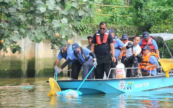 Onn Hafiz (depan) dan Raven Kumar (kiri) mengutip sampah dalam Program Pembersihan Sungai Tebrau dan Pelancaran Bot Scavenger Perangkap Sampah di Sungai Tebrau, Johor Bahru, pada Sabtu.