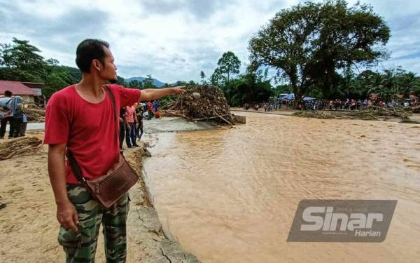 Mohd Kamal menunjukkan jambatan batu yang runtuh akibat arus deras dalam kejadian banjir lumpur pada Isnin.