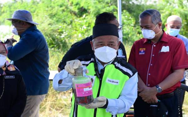 Tuan Ibrahim menunjukkan sampel air yang diambil.