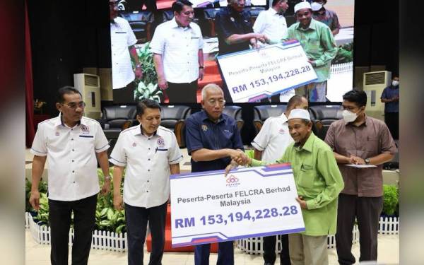 Mahdzir (tiga dari kiri) menyampaikan replika cek bernilai RM153 juta kepada wakil peserta di majlis penyerahan keuntungan boleh agih interim 1 Felcra Berhad di Kuala Nerang.