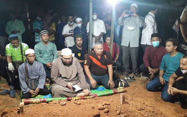 Bapa mangsa, Rosman Ahmad (duduk kanan) dan ahli keluarga serta kenalan semasa membaca talkin di Tanah Perkuburan Islam Kampung Bakar Batu, Johor Bahru, pada Selasa.