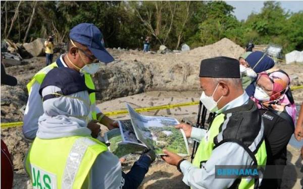 Tuan Ibrahim (kanan) melihat peta kawasan pembuangan sisa toksik di tapak pelupusan sampah haram di Kampung Semarang di sini pada Selasa. - Foto Bernama