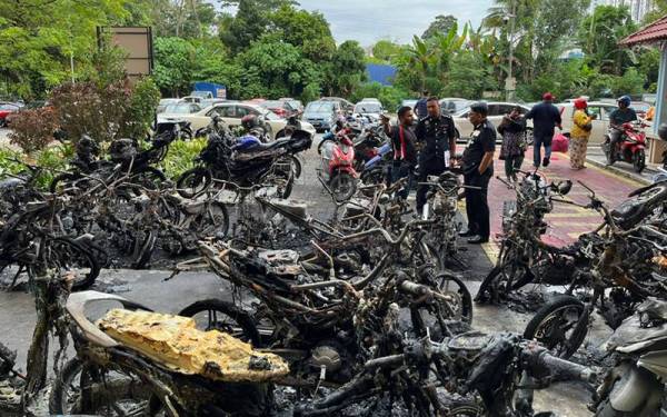 Muhammad Idzam (kanan) melihat keadaan motosikal yang musnah terbakar di PPR Kampung Muhibbah di sini pada Rabu.