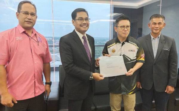 Lian Ker (dua dari kanan) menyerahkan surat kelulusan peruntukan RM500,000 untuk kerja baik pulih Stadium Hoki Kuantan kepada Hamdan di Kompleks Bandaraya Kuantan pada Rabu.