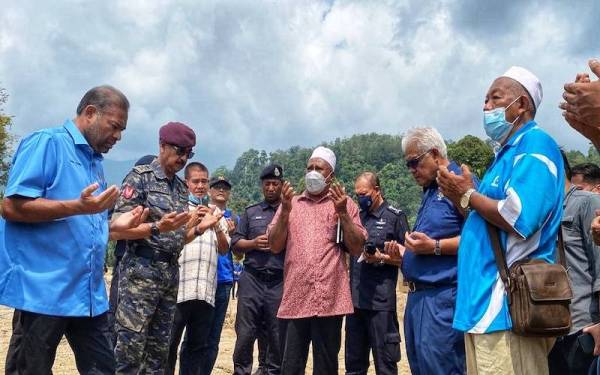 Hamzah (dua dari kanan) membaca doa ketika melawat lokasi kejadian di Kampung Iboi, Baling pada Jumaat.