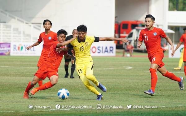 Pemain B-19 negara, Azannis Adzri Abdul Halim (tengah) cuba melepasi kawalan pertahanan Singapura dalam aksi di Stadium Madya, Senayan, Jakarta pada Sabtu. - Foto FB FAM