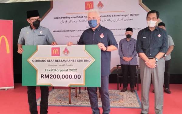 Azmir (kiri) menyampaikan replika cek zakat korporat berjumlah RM200,000 kepada Tengku Mohamad Rizam.