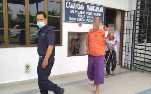 Suspek menunjukkan isyarat jari kepada media ketika dibawa keluar dari Cawangan Mahkamah Ibu Pejabat Polis Daerah Kuala Muda pada Selasa.