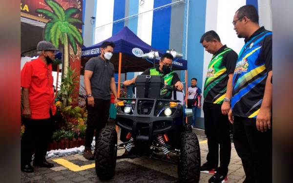 Sulaiman (tengah) menaiki kenderaan lasak pelbagai bentuk permukaan bumi (ATV) bagi penggunaan aktiviti pertanian yang dipamerkan sempena Sambutan Hari Peladang, Penternak dan Nelayan (HPPN) peringkat Melaka pada Sabtu. - Foto Bernama