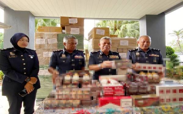 Mohd Nasir (dua dari kanan) menunjukkan 671,000 batang rokok putih yang dirampas oleh Kastam Kelantan termasuk kretek yang disembunyikan dalam sebuah van jenis Toyota Hiace di tepi lorong sebuah kampung, di Kota Bharu pada Rabu.