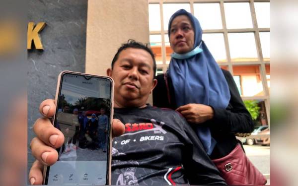 Mohd Abdul Sani menunjukkan gambar arwah anaknya (kanan) bersama isteri, Masitah ketika ditemui di pekarangan Jabatan Forensik HPP.