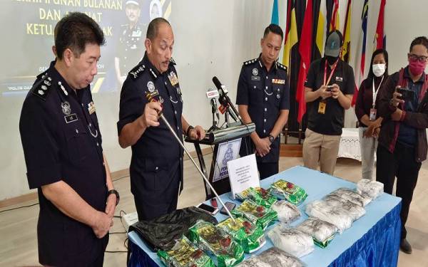 Mior Faridalathrash (dua dari kiri) menunjukkan heroin dan methamphetamine yang berjaya dirampas daripada seorang lelaki di Pantai Remis, Manjung pada Isnin.