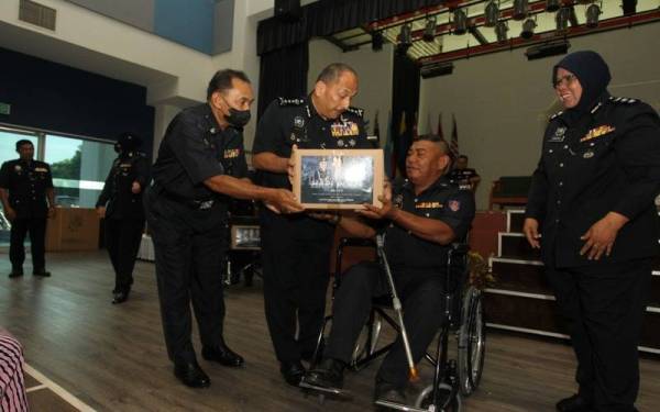 Mior Faridalathrash (dua dari kiri) menyampaikan sumbangan kotak makanan dan kerusi roda kepada salah seorang anggota pada Perhimpunan Bulanan Ketua Polis Perak di PLPGU di Ipoh.